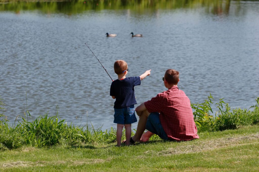 Father and son fishing by lake