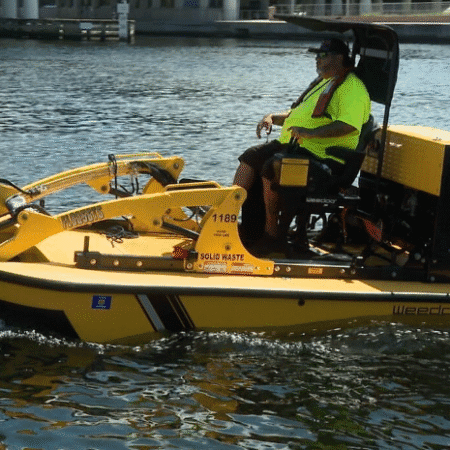 Yellow water cleanup skimmer boat with operator